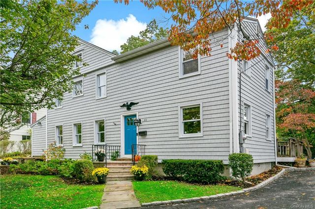 a front view of a house with a yard and potted plants