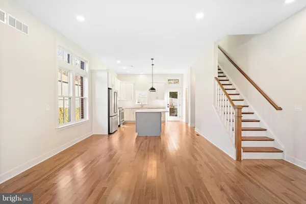 a view of a kitchen with wooden floor electronic appliances and stairs