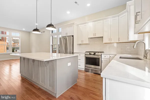 a kitchen with stainless steel appliances kitchen island granite countertop a sink a stove and a refrigerator