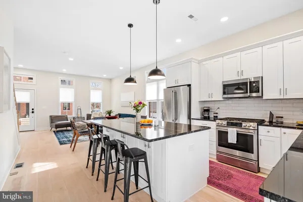 a kitchen with stainless steel appliances kitchen island granite countertop a stove a sink a dining table and chairs