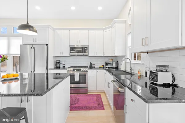 a kitchen with stainless steel appliances granite countertop a sink stove and refrigerator