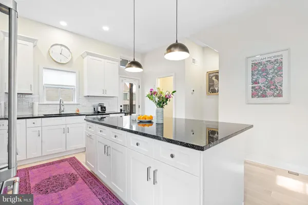 a kitchen with stainless steel appliances granite countertop a sink a stove a dining table and chairs