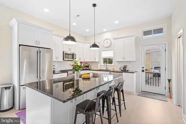a kitchen with stainless steel appliances granite countertop a stove a sink a refrigerator a center island a table and chairs