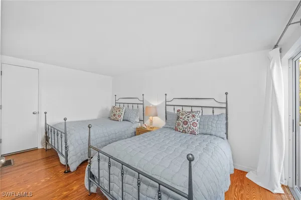 a bedroom with two beds and wooden floor