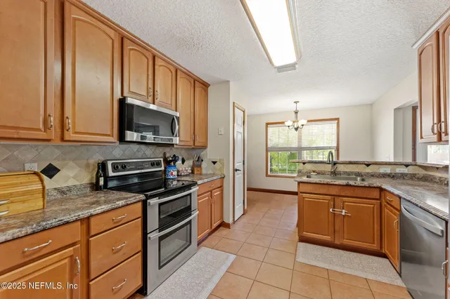 a kitchen with stainless steel appliances granite countertop wooden cabinets a sink and dishwasher a stove top oven with wooden floor