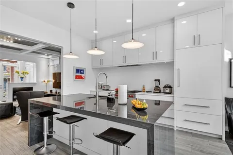 a kitchen with stainless steel appliances granite countertop a stove a refrigerator a sink a dining table and chairs with wooden floor