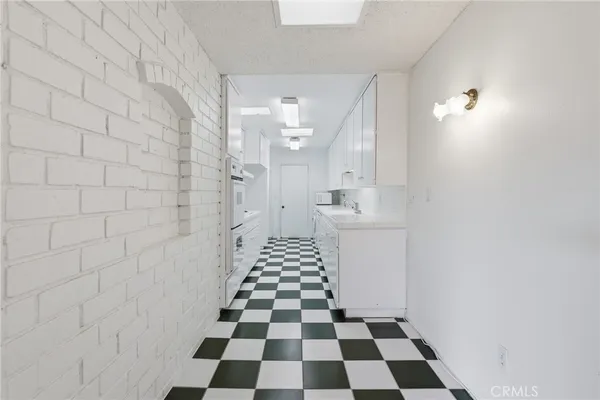 a hallway with a black white checkered floor and a white refrigerator