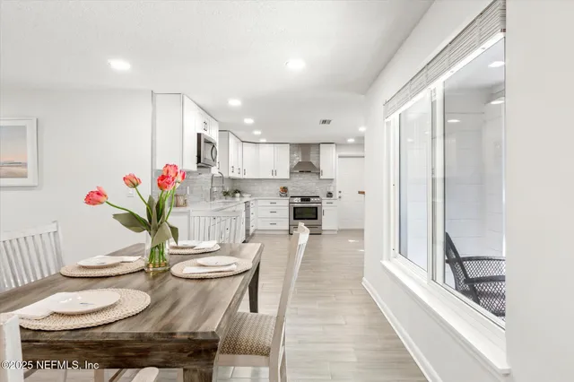 a kitchen with stainless steel appliances kitchen island granite countertop a stove a sink a table and chairs