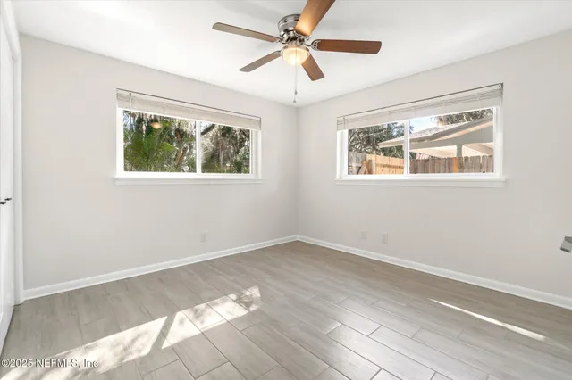 a view of an empty room with wooden floor and a window