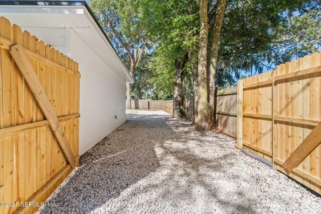 a view of a backyard with wooden fence and large trees