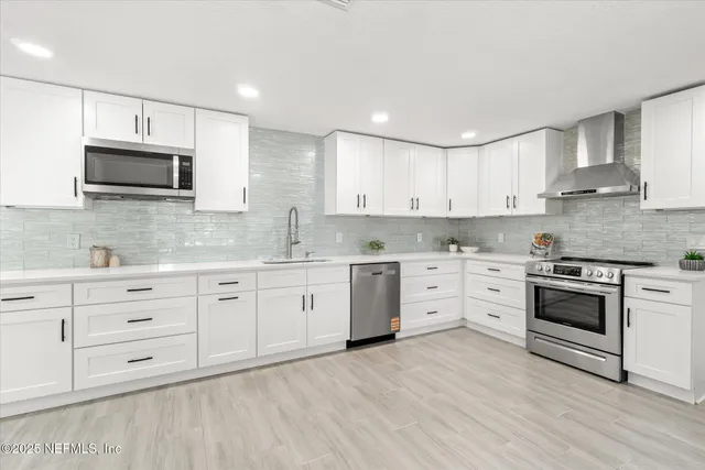 a kitchen with stainless steel appliances granite countertop a stove a sink and white cabinets