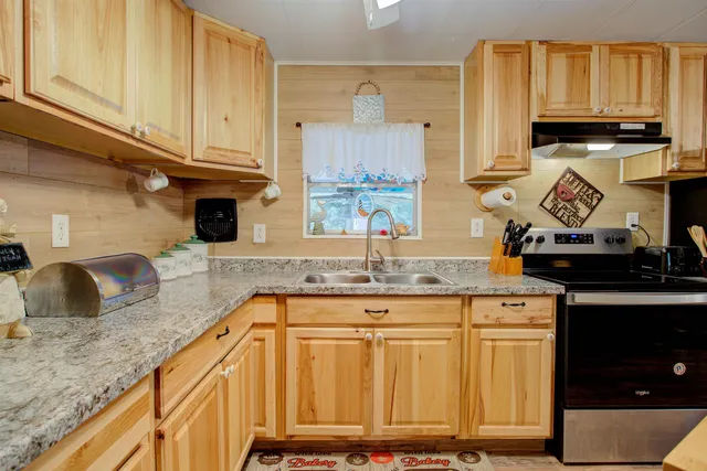 a kitchen with granite countertop a sink a stove and cabinets