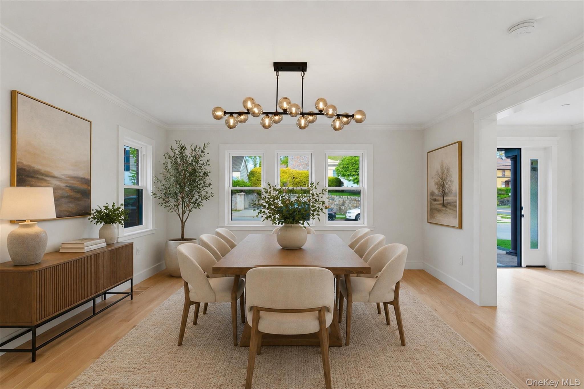 40 Calhoun Avenue New Rochelle, NY 10801 - Photo 9 of 49 Bright dining area featuring light wood-finish flooring, a contemporary linear chandelier, multiple windows with white trim, and white crown molding