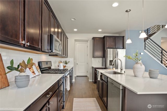 a kitchen with stainless steel appliances a sink a stove top oven a counter space and cabinets