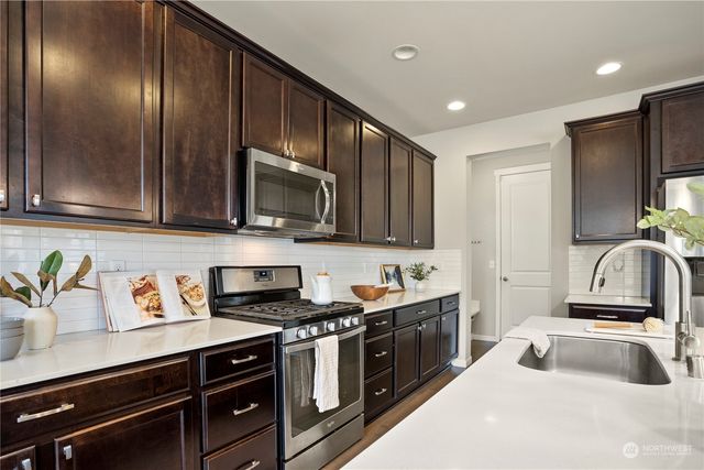 a kitchen with stainless steel appliances granite countertop a sink stove and microwave