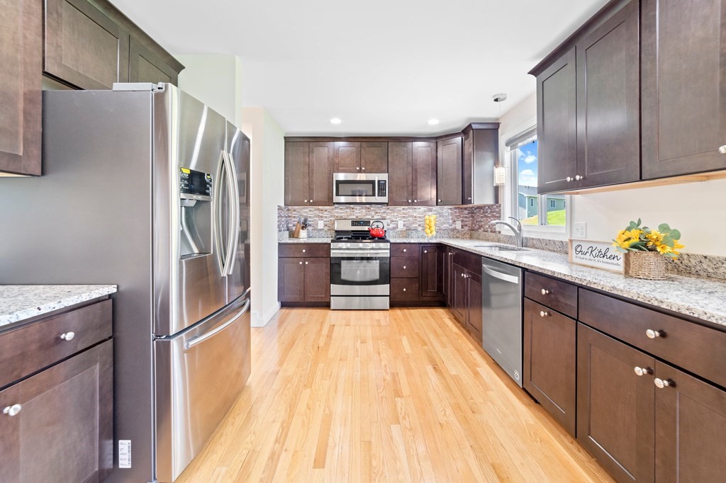 311 Littleton Road, Unit 60 Chelmsford, MA 01824 - Photo 21 of 42 a large kitchen with stainless steel appliances granite countertop a refrigerator a stove a sink dishwasher and wooden cabinets with wooden floor