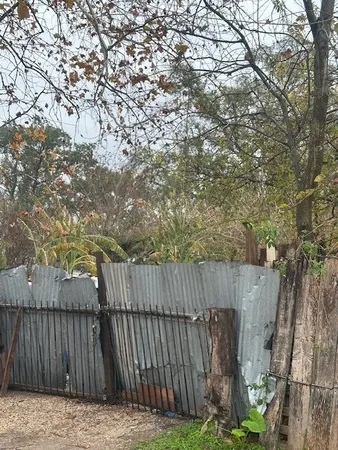 a view of backyard with a trees and wooden fence