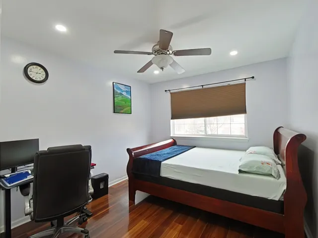 a bedroom with a bed desk and chair with wooden floor