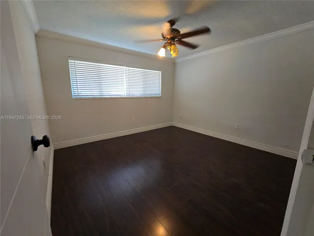a view of an empty room with wooden floor and a ceiling fan
