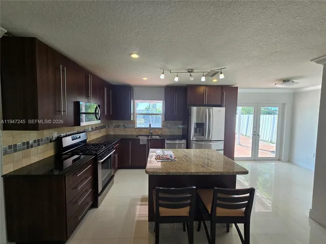 a kitchen with stainless steel appliances granite countertop a refrigerator stove microwave and sink