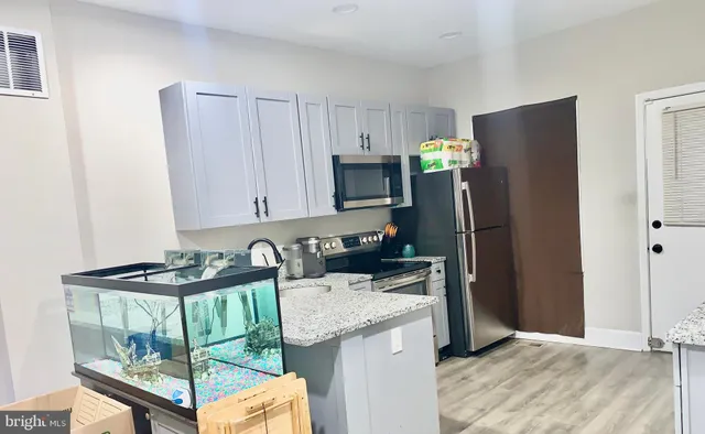 a kitchen with granite countertop a refrigerator and a stove top oven