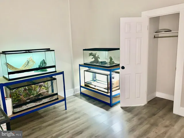 a view of an empty room with wooden floor fireplace and a window