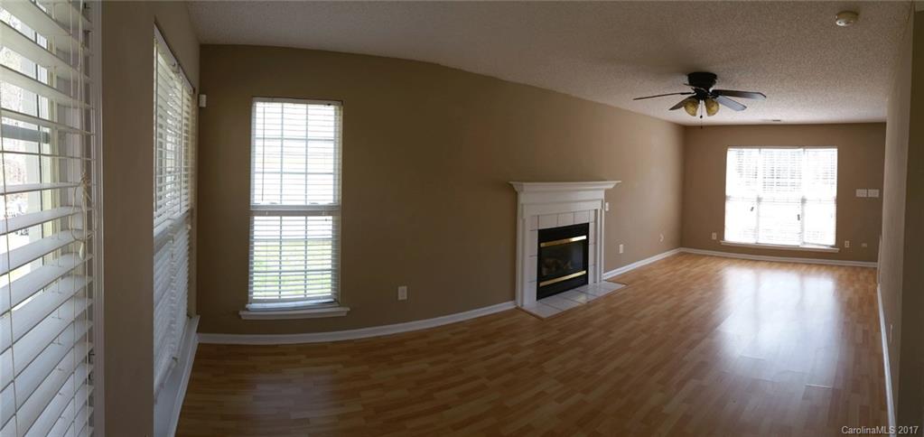 11203 Gold Pan Road Charlotte, NC 28215 - Photo 2 of 15 an empty room with wooden floor a fireplace and windows