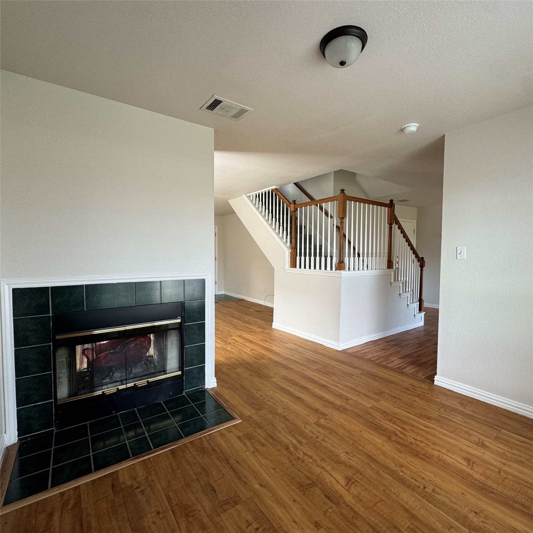 4735 Castleman Drive Austin, TX 78724 - Photo 3 of 16 Unfurnished living room featuring stairs, dark wood-type flooring, a fireplace, and a textured ceiling