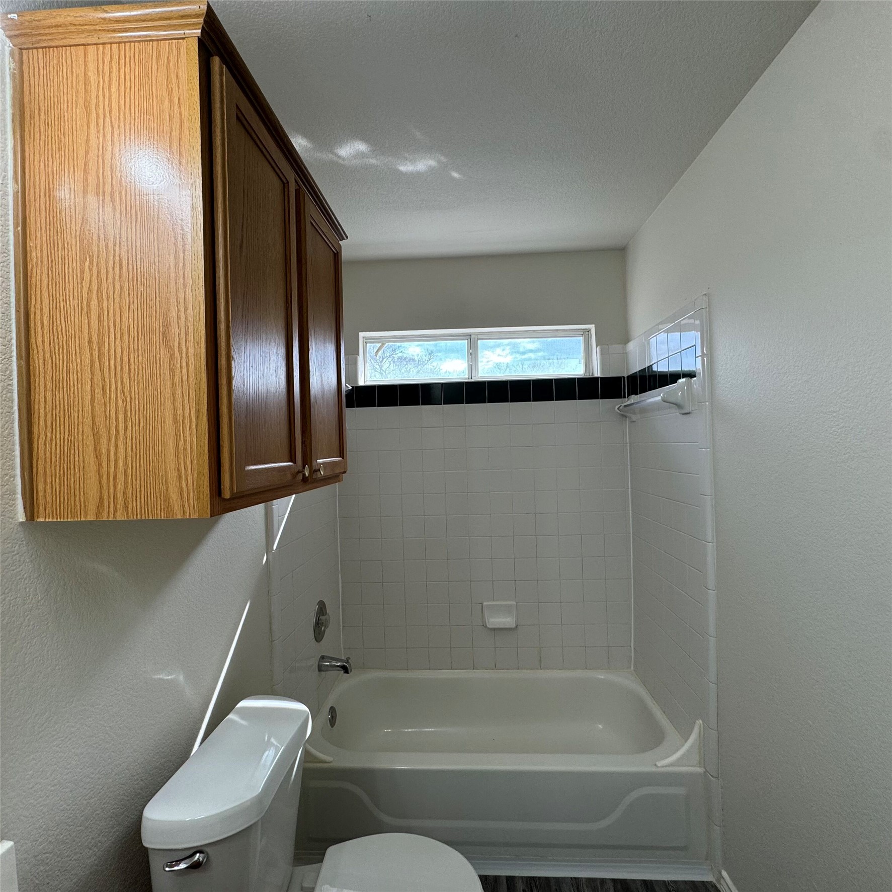 4735 Castleman Drive Austin, TX 78724 - Photo 8 of 16 Bathroom featuring a textured wall, shower / washtub combination, and a textured ceiling