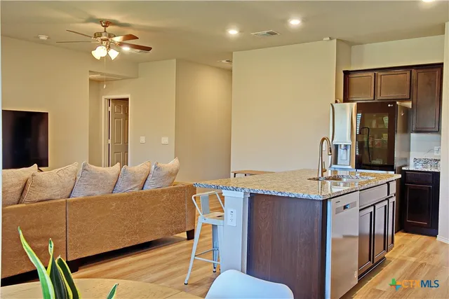 a living room with stainless steel appliances kitchen island granite countertop furniture and a refrigerator
