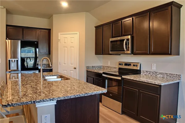 a kitchen with kitchen island granite countertop a stove top oven microwave and cabinets
