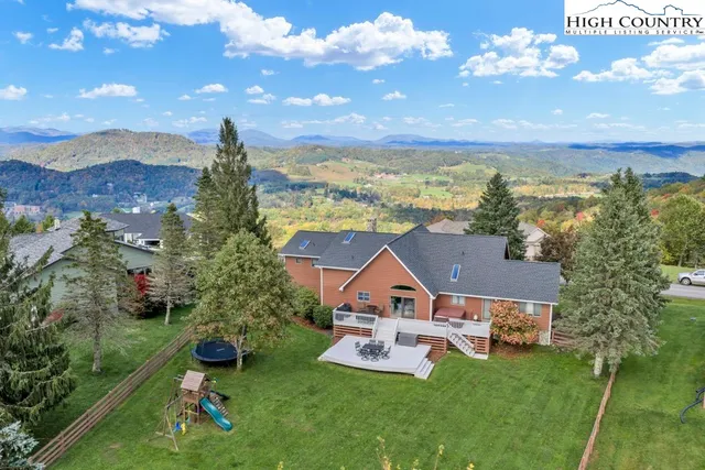 an aerial view of a house with swimming pool garden and mountain view in back