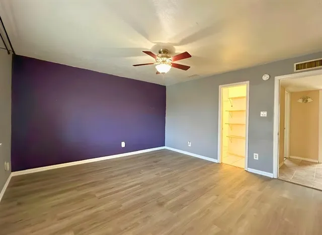 a view of an empty room with chandelier fan and wooden floor