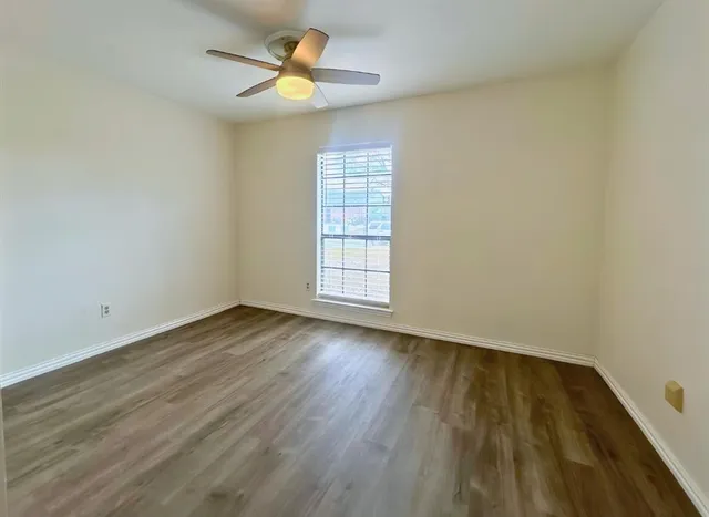 a view of an empty room with window and chandelier fan