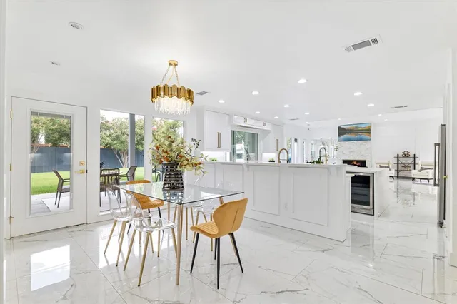 a dining room filled chandelier and kitchen view