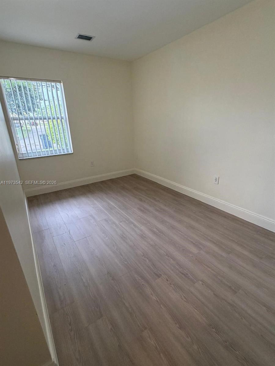 5252 Southwest 139th Place, Unit 5252 Miami, FL 33175 - Photo 13 of 18 an empty room with wooden floor and windows