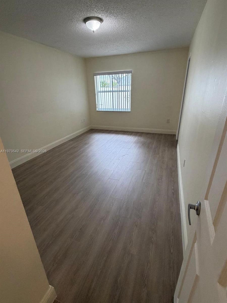 5252 Southwest 139th Place, Unit 5252 Miami, FL 33175 - Photo 15 of 18 wooden floor in an empty room with a window