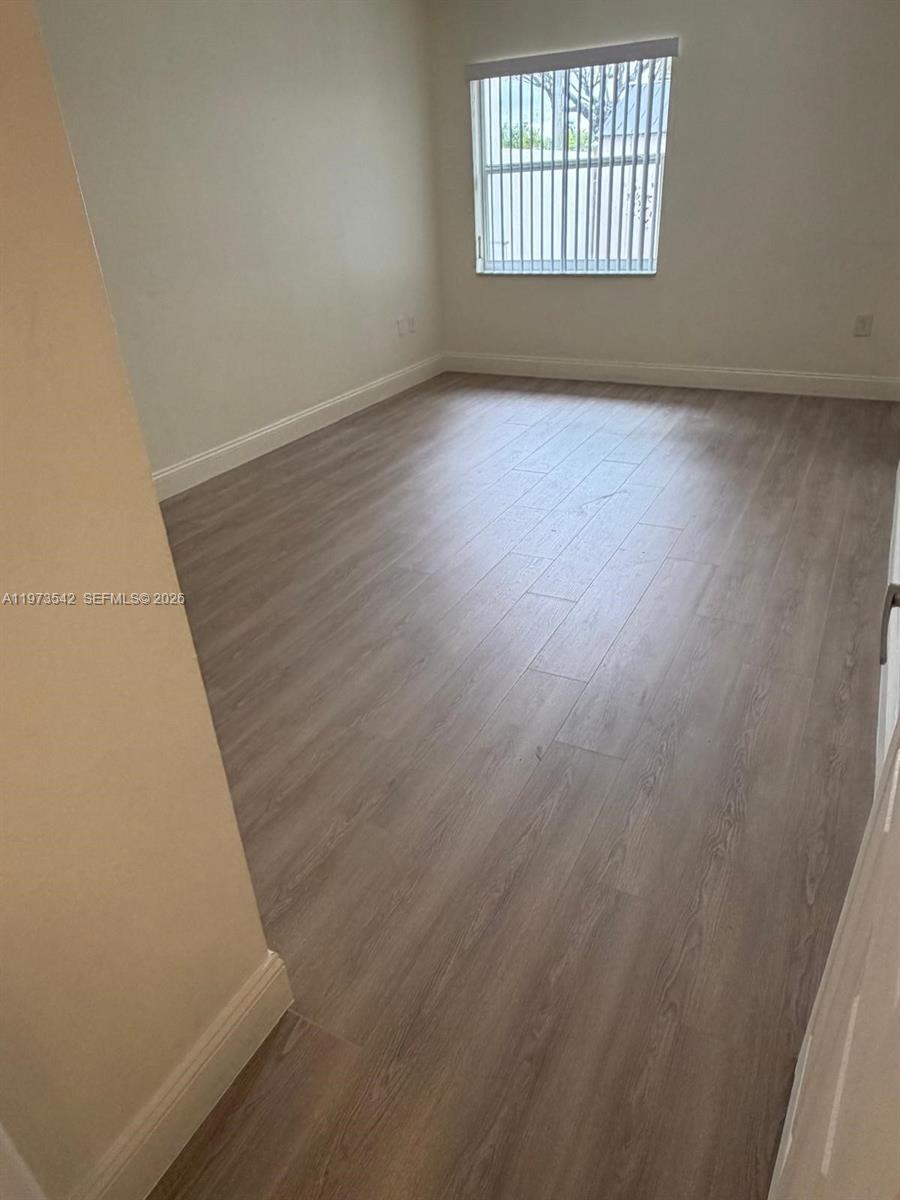 5252 Southwest 139th Place, Unit 5252 Miami, FL 33175 - Photo 16 of 18 an empty room with wooden floor and windows