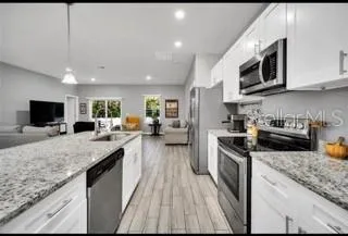 a large kitchen with stainless steel appliances granite countertop a stove a sink and a microwave