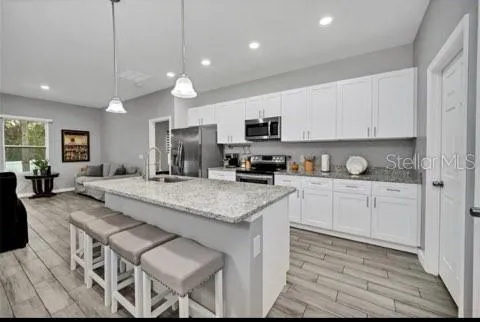 a kitchen with stainless steel appliances granite countertop a stove a sink a oven a dining table and chairs with wooden floor