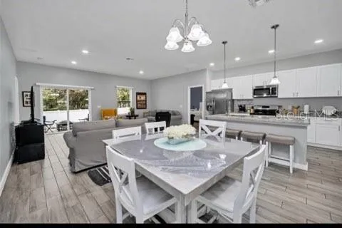 a view of a dining room with furniture a kitchen and chandelier