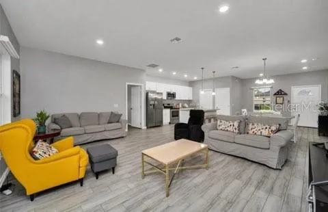a living room with furniture kitchen view and a wooden floor