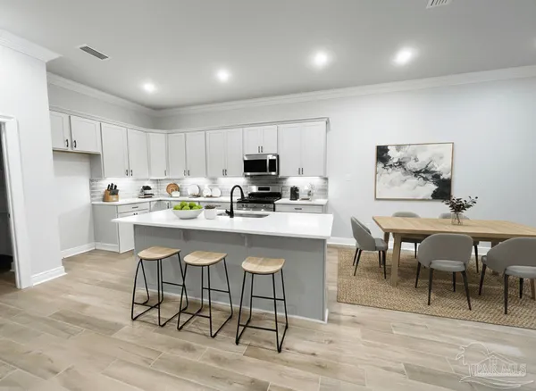 a kitchen with stainless steel appliances granite countertop a stove a sink a microwave a dining table and chairs