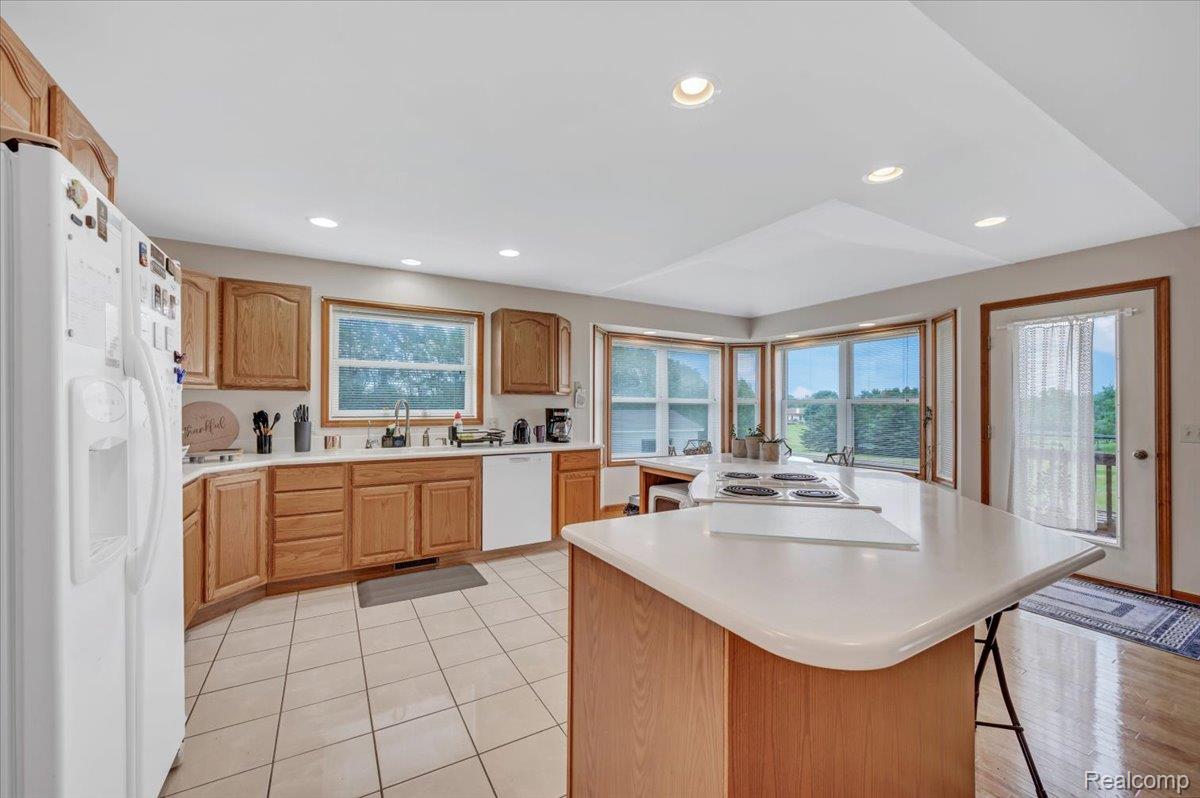 2551 Marathon Road Lapeer, MI 48446 - Photo 13 of 33 Kitchen featuring wood cabinetry, white countertops, a large center island with a built-in cooktop, recessed lighting, and a bay window