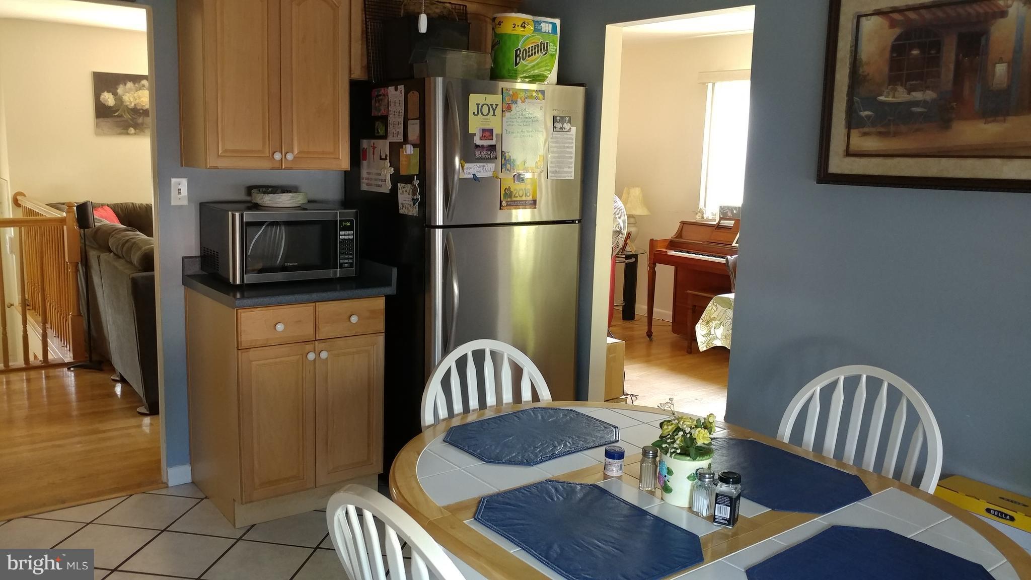 6002 Chesworth Road Baltimore, MD 21228 - Photo 6 of 26 a kitchen with stainless steel appliances kitchen island granite countertop a refrigerator a stove a microwave oven with a dining table and chairs