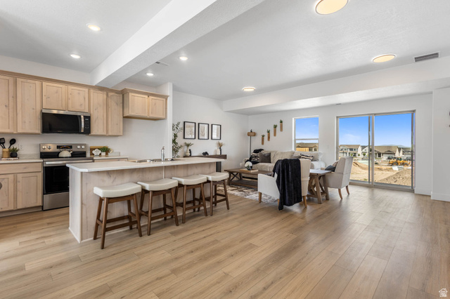 636 West Caroles Way, Unit 7 Tooele, UT 84074 - Photo 7 of 31 Open concept living area featuring light wood-finish flooring, recessed lighting, and a kitchen island with seating