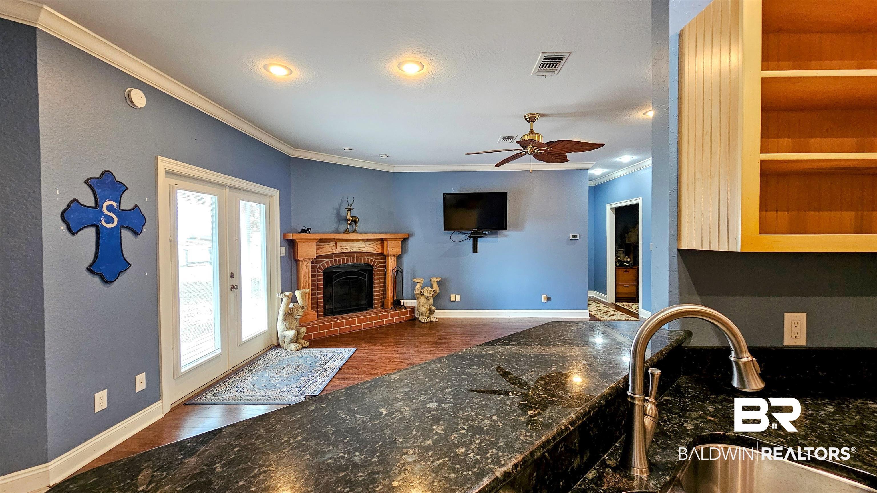 9275 Crawford Road Elberta, AL 36530 - Photo 18 of 28 Living room featuring crown molding, dark wood-type flooring, a brick fireplace, a ceiling fan, and recessed lighting