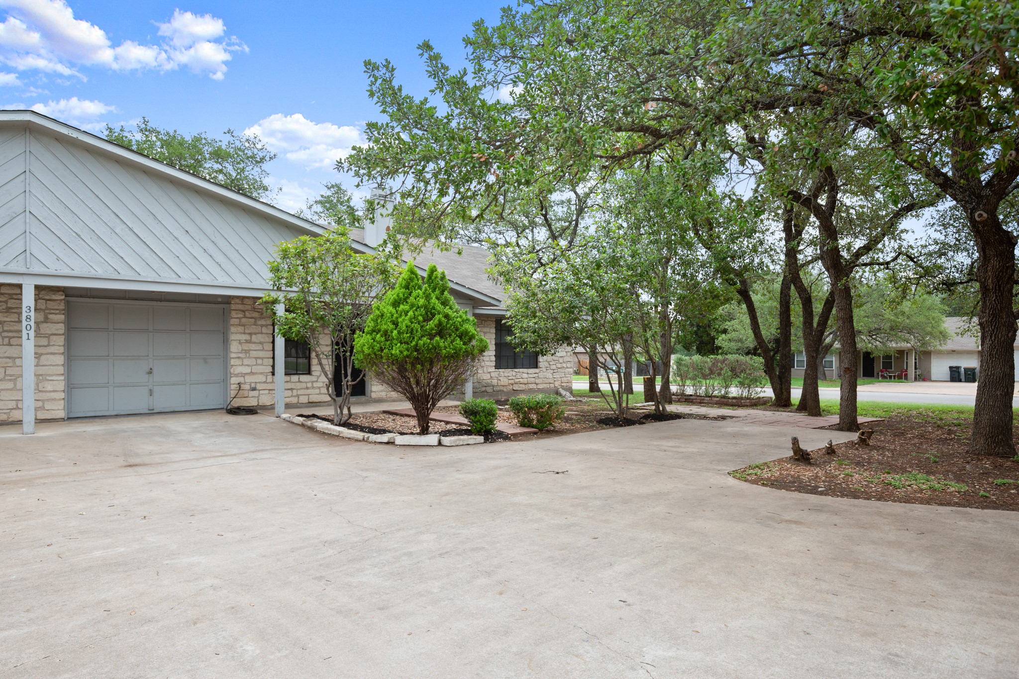 3801 Foust Trail, Unit B Georgetown, TX 78628 - Photo 2 of 31 The property features a stone exterior with a gray garage door and a gray metal roof