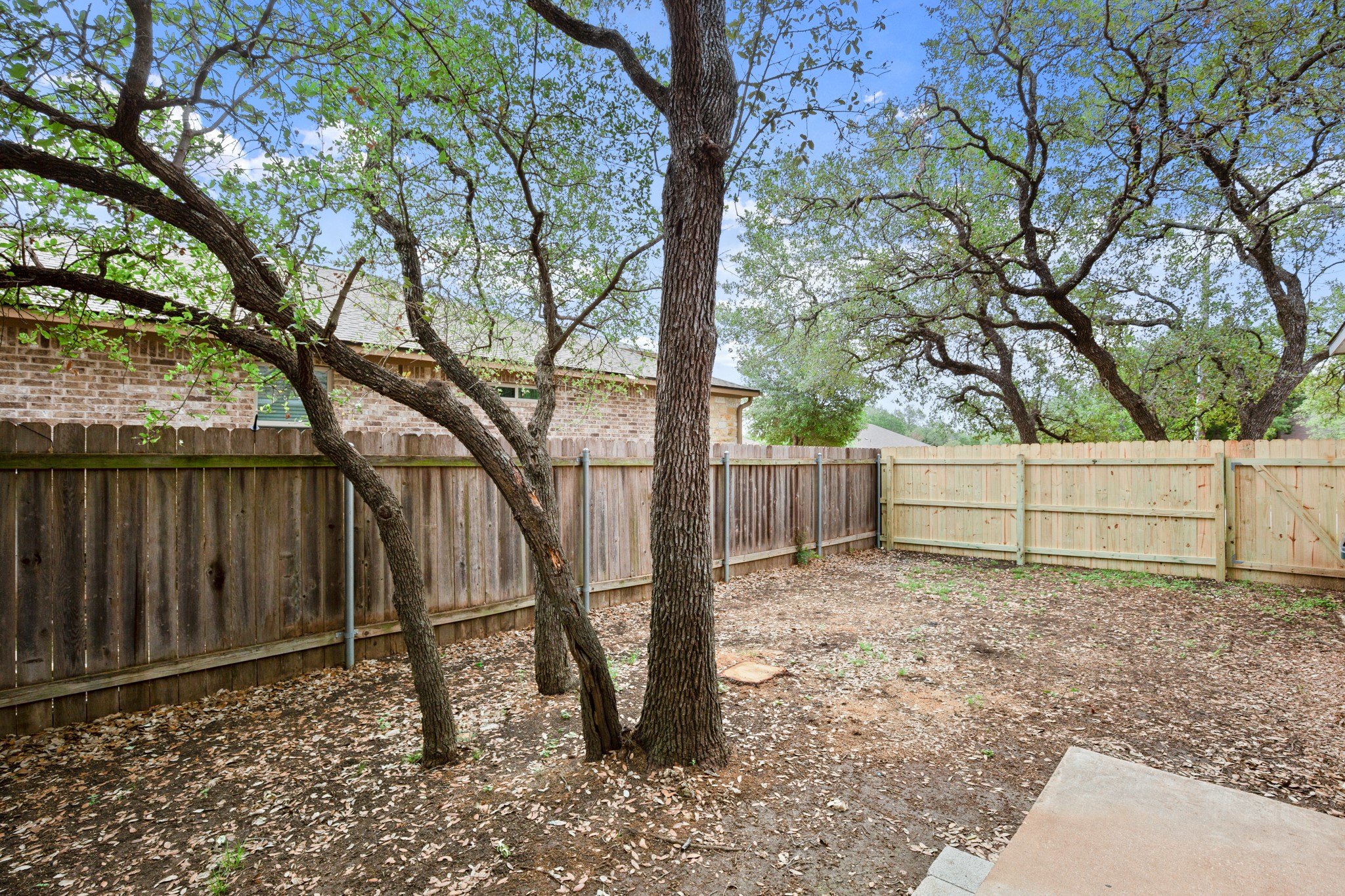 3801 Foust Trail, Unit B Georgetown, TX 78628 - Photo 23 of 31 The property includes a spacious yard with mature trees, surrounded by a combination of wooden fencing