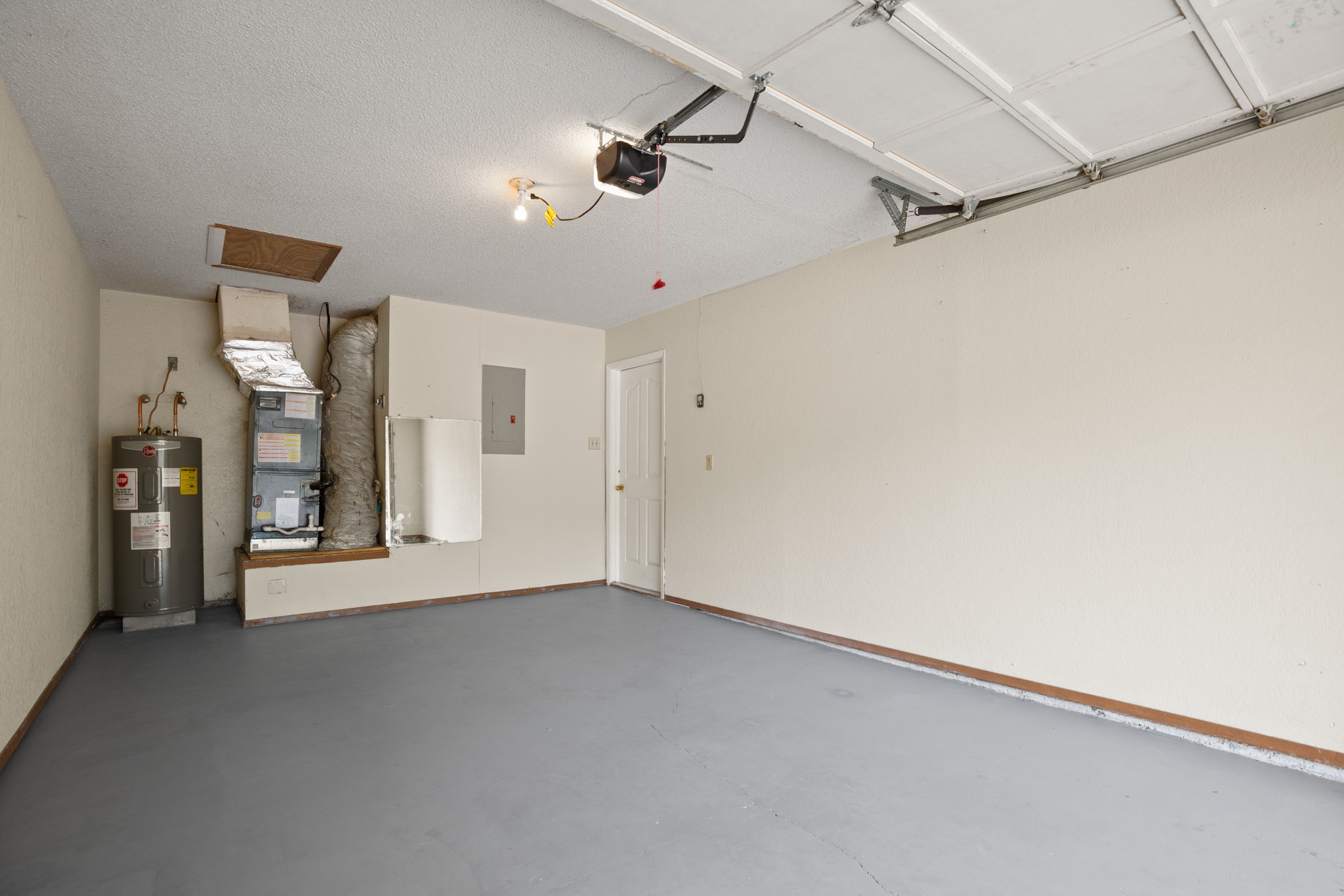 3801 Foust Trail, Unit B Georgetown, TX 78628 - Photo 26 of 31 The property features a garage with a ceiling-mounted garage door opener, painted walls, and a painted floor